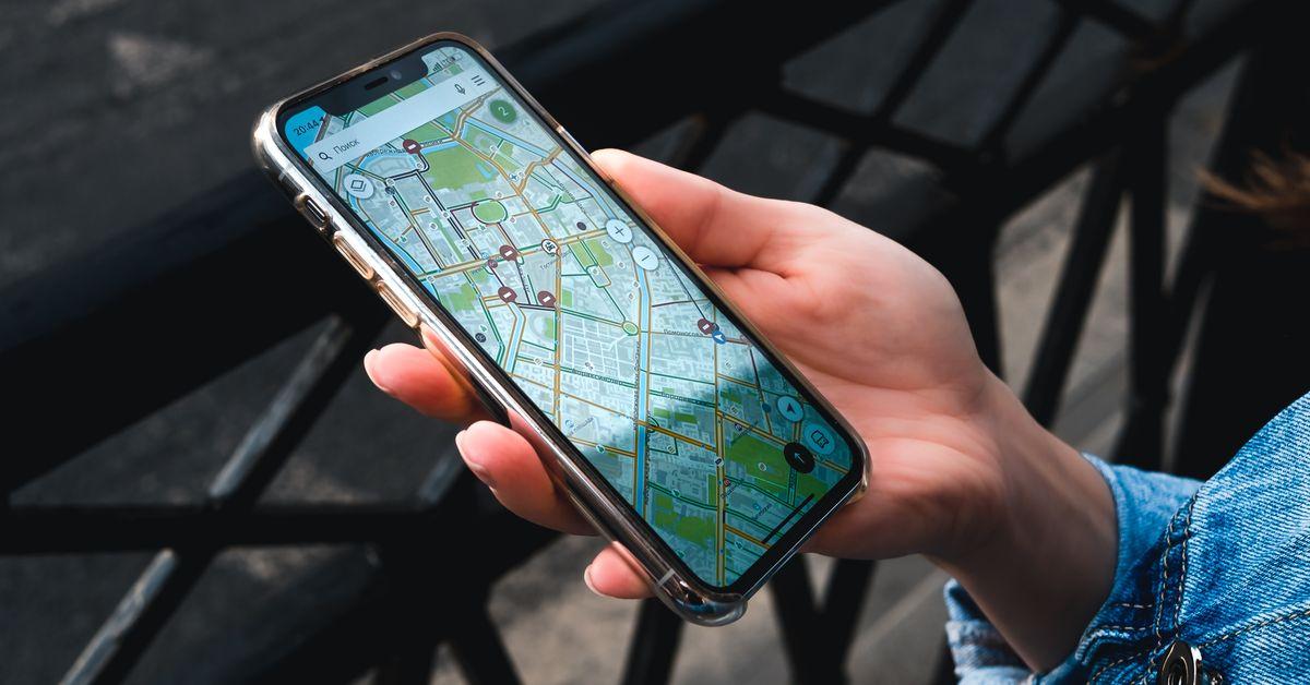 Hand holding a smartphone displaying a map application outdoors